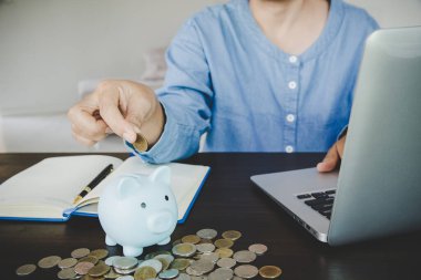  woman hand putting money into piggy for saving money wealth and financial concept.