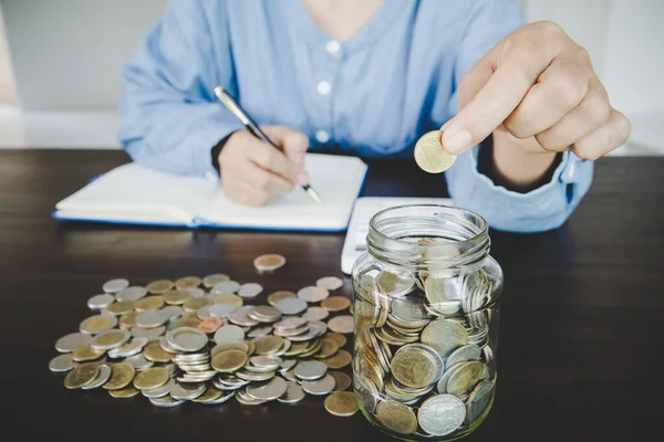 woman hand putting money into jar for saving money wealth and financial concept.