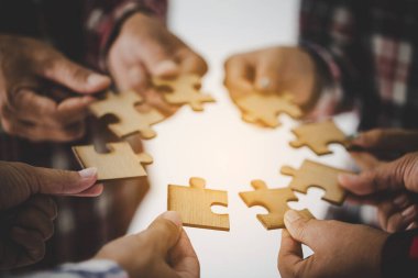 Hands holding piece of blank jigsaw puzzle for teamwork workplace success and strategy concept.