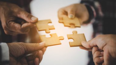 Hands holding piece of blank jigsaw puzzle for teamwork workplace success and strategy concept.