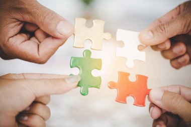 Hands holding piece of blank jigsaw puzzle for teamwork workplace success and strategy concept.