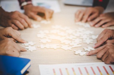 İş adamları ve bulmacalar ahşap masada, takım çalışması konsepti
