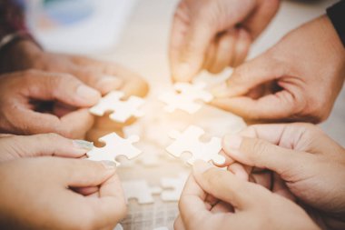 Hands holding piece of blank jigsaw puzzle for teamwork workplace success and strategy concept.
