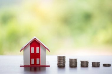 House model and money coins stacks with blur nature background. Savings plans for home, loan, investment, mortgage, finance and banking about house concept.
