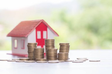 House model and money coins stacks with blur nature background. Savings plans for home, loan, investment, mortgage, finance and banking about house concept.