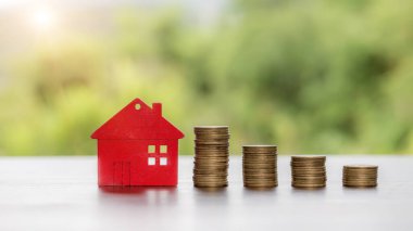 House model and money coins stacks with blur nature background. Savings plans for home, loan, investment, mortgage, finance and banking about house concept.