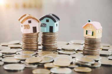 House model and money coins stacks on blur table background. Savings plans for home, loan, investment, mortgage, finance and banking about house concept.
