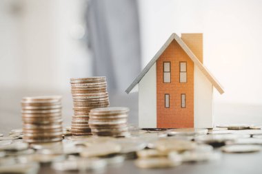 House model and money coins stacks on blur table background. Savings plans for home, loan, investment, mortgage, finance and banking about house concept.