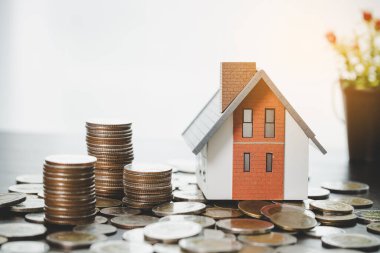 House model and money coins stacks on blur table background. Savings plans for home, loan, investment, mortgage, finance and banking about house concept.