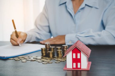 House model with stack coins, business hand is planning savings money of coins for buy home. concept for property ladder, mortgage with real estate investment and saving or investment for a house