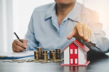 House model with stack coins, business hand is planning savings money of coins for buy home. concept for property ladder, mortgage with real estate investment and saving or investment for a house
