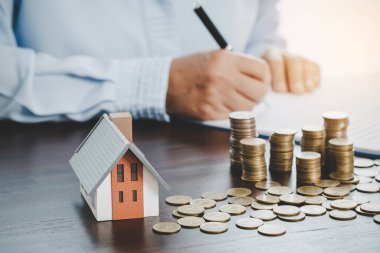 House model with stack coins, business hand is planning savings money of coins for buy home. concept for property ladder, mortgage with real estate investment and saving or investment for a house