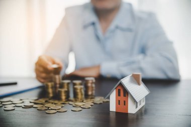 House model with stack coins, business hand is planning savings money of coins for buy home. concept for property ladder, mortgage with real estate investment and saving or investment for a house