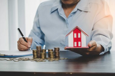 House model with stack coins, business hand is planning savings money of coins for buy home. concept for property ladder, mortgage with real estate investment and saving or investment for a house