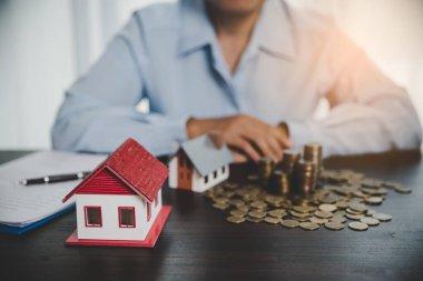 House model with stack coins, business hand is planning savings money of coins for buy home. concept for property ladder, mortgage with real estate investment and saving or investment for a house