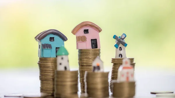 House model and money coins stacks with blur nature background. Savings plans for home, loan, investment, mortgage, finance and banking about house concept.