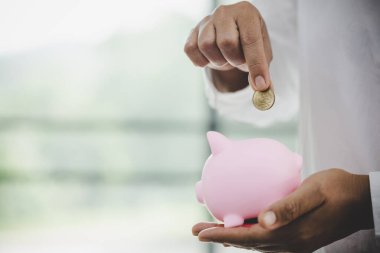  woman hand putting money into piggy for saving money wealth and financial concept.