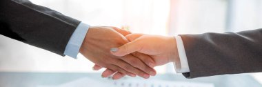 Professional businessman and businesswoman partners shaking hands together with business success deal and agreement. Hands business teamwork handshaking at office desk. Partnership banner copy space