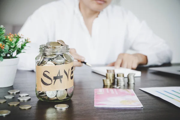 a woman makes calculations, checks her finances, makes notes in a notebook and sets aside some of the funds