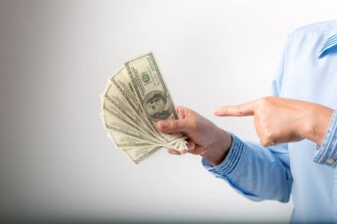 I'm rich! Portrait of successful happy woman with fancy brown hair pointing to dollar bills, showing money and boasting lottery winning, big profit. indoor studio shot isolated on gray background