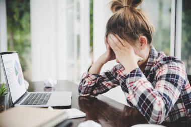 woman sitting down, his face unsettled. At the computer desk she has headaches and stress. Cause of hard work and insufficient rest.