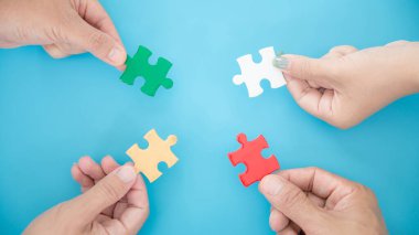 High Angle View Of Businesspeople Hand Solving Jigsaw Puzzle On Blue Background