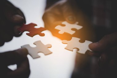 Hands holding piece of blank jigsaw puzzle for teamwork workplace success and strategy concept.