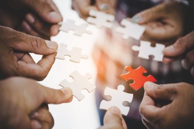 Hands holding piece of blank jigsaw puzzle for teamwork workplace success and strategy concept.