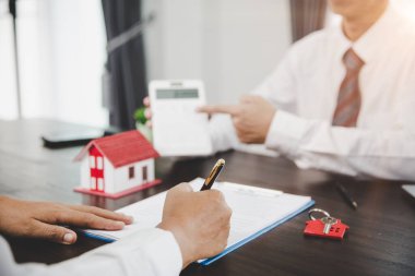 Real estate agents offer contracts to purchase or rent residential. Business person hands holding home model, small building red house. Mortgage property insurance moving home and real estate concept