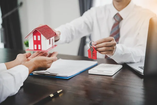 Business person hands holding home model, small building red house. Real estate agents offer contracts to purchase or rent residential. Mortgage property insurance moving home and real estate concept