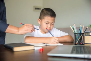 Young student distance learning virtual distance online class on video call virtual lesson with mother, studying at home using laptop computer. Parent or tutor teaching child boy with remote education