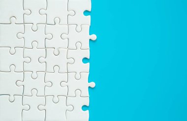 White part of jigsaw puzzle pieces on blue background. concepts of problem solving, business success, teamwork, Team playing jigsaw game incomplete, Texture photo with copy space for text