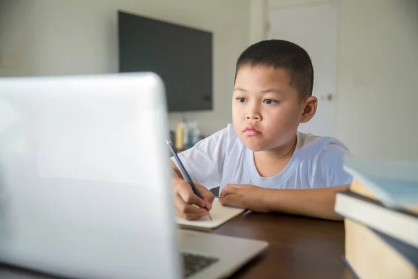 Young student distance learning virtual distance online class on video call virtual lesson, technology studying at home using laptop computer. Parent or tutor teaching child boy with remote education.