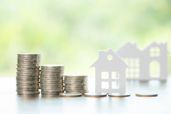 Дом и сложить монеты с фоном, чтобы сэкономить на жилье. Денежный финансовый план по кредитам или ипотекам и инвестициям в банке. Концепция страхования домов и роста недвижимости