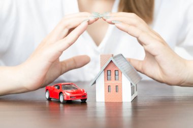 young woman use two hand to protect house model and toy car. real estate, insurance and property concepts