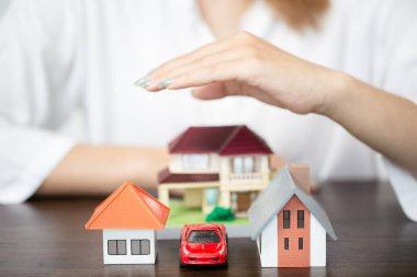 young woman use left hand to protect house model and toy car. real estate, insurance and property concepts