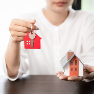 Woman holding house model and house key in hand.insurance, estate and property concept