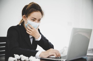 Sick young asian business woman wearing protective face mask having cold fever.Health problems concept