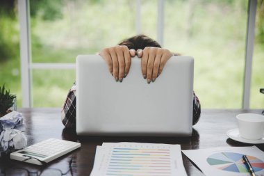 Tired businesswoman working on a computer Portrait of stressed young woman comfortably with headache at desk. Exhausted business woman working on laptop at office.