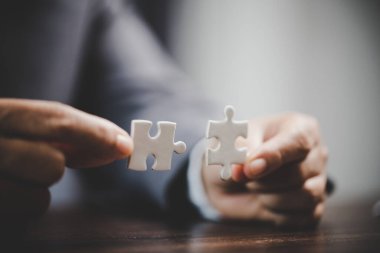 Business woman person hand holding puzzle piece idea for strategy and solution. Closeup part of two white jigsaw connect together. Concept of join cooperation success teamwork-problem corporate team