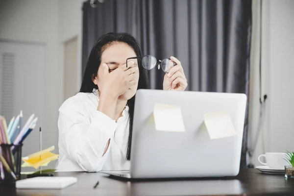 Young business woman person sleepy and has frustration eye problems with cephalalgia disease from using laptop computer on her office desk. Stressed female employee tired and exhausted from overwork.