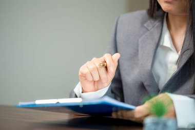 Workplace closeup person professional businesswoman sitting at desk hold pen signing or signature contract paper. Employee woman writing agreement document on paperwork form corporate at work office