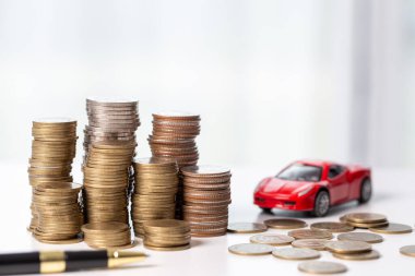 Arka planda bozuk para yığını olan oyuncak araba. Ulaşım finansmanını yönetmeyi planlıyorum. Araba sigortası işi kavramı, tasarruf satın alma - yeni araba için vergi ve kredi ile satış.