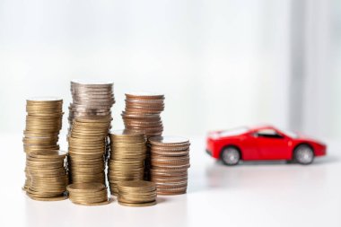 Arka planda bozuk para yığını olan oyuncak araba. Ulaşım finansmanını yönetmeyi planlıyorum. Araba sigortası işi kavramı, tasarruf satın alma - yeni araba için vergi ve kredi ile satış.