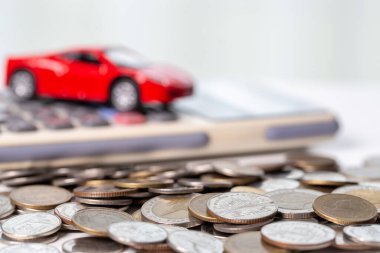 Arka planda bozuk para yığını olan oyuncak araba. Ulaşım finansmanını yönetmeyi planlıyorum. Araba sigortası işi kavramı, tasarruf satın alma - yeni araba için vergi ve kredi ile satış.