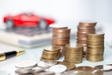 Arka planda bozuk para yığını olan oyuncak araba. Ulaşım finansmanını yönetmeyi planlıyorum. Araba sigortası işi kavramı, tasarruf satın alma - yeni araba için vergi ve kredi ile satış.