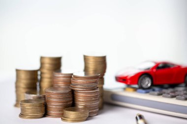 Arka planda bozuk para yığını olan oyuncak araba. Ulaşım finansmanını yönetmeyi planlıyorum. Araba sigortası işi kavramı, tasarruf satın alma - yeni araba için vergi ve kredi ile satış.