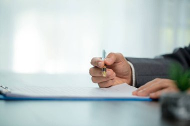 Workplace closeup person professional businesswoman sitting at desk hold pen signing or signature contract paper. Employee woman writing agreement document on paperwork form corporate at work office