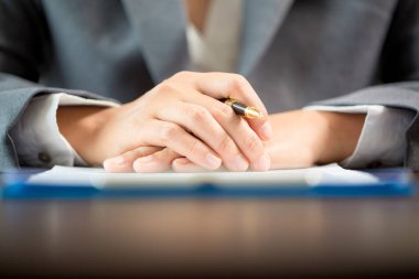 Workplace closeup person professional businesswoman sitting at desk hold pen signing or signature contract paper. Employee woman writing agreement document on paperwork form corporate at work office