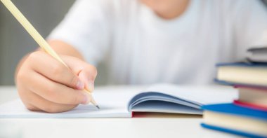 Boy person sitting study indoor at home, Male kid student online learning and doing homework on desk, young child reading and writing a book on table. concept of education, technology cyberspace